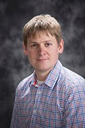 Headshot of Keegan Witt wearing a patterned button shirt